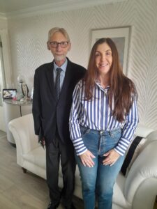 George and Steph stand together in front of Steph's cream leather couch in her living room