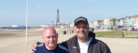 James and Adrian stand in front of Blackpool tower and smile at the camera